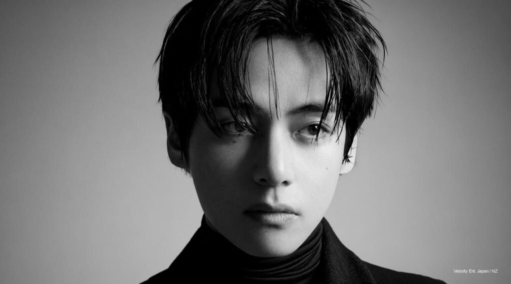 BTS’ V in a long black CELINE coat with a bold red scarf, exuding timeless elegance in teaser image for CELINE Hiver 2026 Paris show.