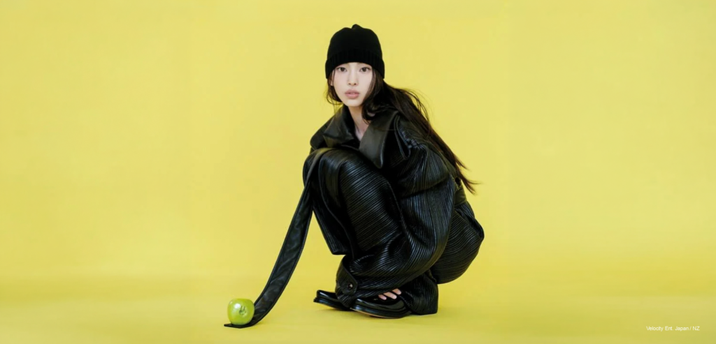 Hyein x Bottega — Dazed Korea September K-Pop News NewJeans Hyein crouches in black pleated leather Bottega look against acid-yellow backdrop, green apple in foreground, Dazed Korea September 2026 cover preview.