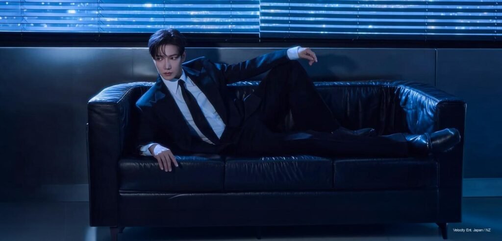 Jun. K in a tailored black suit posing in a blue-lit modern room for the “Your Lips” concept photos.