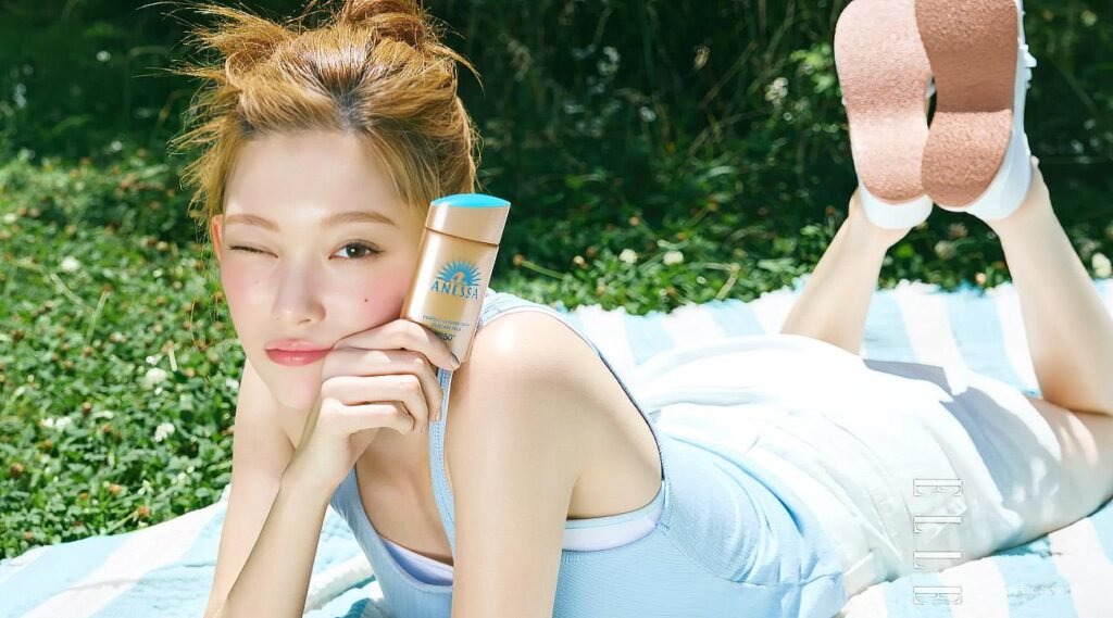 Tsuki for ELLE Korea x Anessa, August 2026 Billlie’s Tsuki poses in a sunlit ELLE Korea x Anessa pictorial, holding sunscreen and winking on a grassy outdoor set.