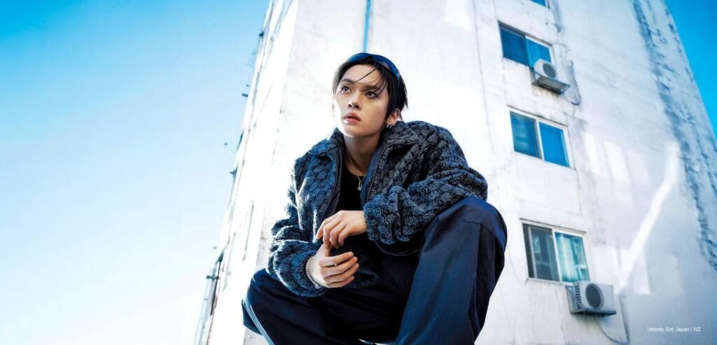 Stray Kids Lee Know W Korea x Gucci Stray Kids member Lee Know crouching in an industrial white architectural setting wearing a Gucci textured fleece jacket and dark trousers for W Korea.