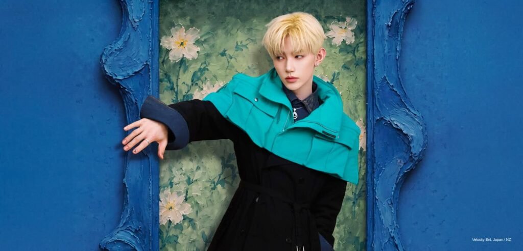 Zhang Hao – VOGUE Forces of Fashion Cover Zhang Hao framed inside a textured blue painted opening against a floral background, wearing a navy trench coat and turquoise capelet.